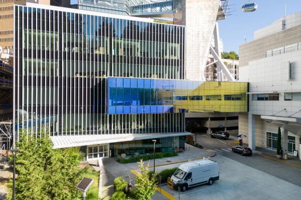 Building with several stories and all glass facing the patient drop off area and a walking bridge connecting to the neighboring building. Building with several stories and all glass facing the patient drop off area and a walking bridge connecting to the neighboring building.